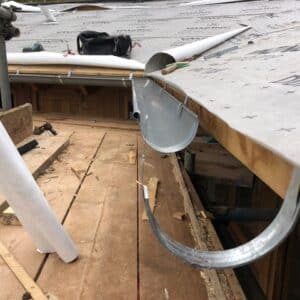 Close up of Zinc guttering being attached to a new wooden roof.