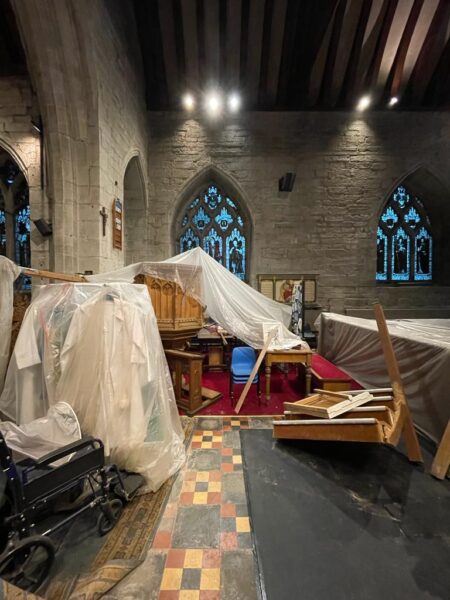 Inside a country church, the pulpit and pews have been covered with tarpaulin. Church Re-ordering scheme by communion architects Hereford