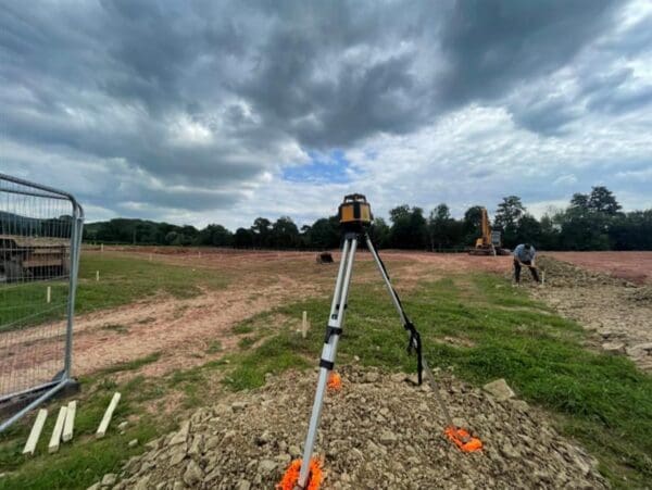 An open field in the countryside with a camera set up on a tripod for site survey. Communion Architects Hereford